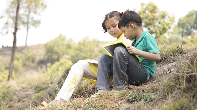 Portrait of Indian boy and girl doing homework outdoors