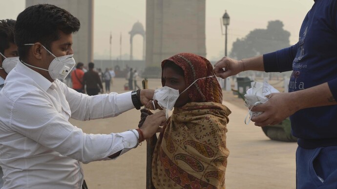 People are helping each other in wearing masks in New Delhi. (Photo: PTI) People are helping each other in wearing masks in New Delhi. (Photo: PTI)
