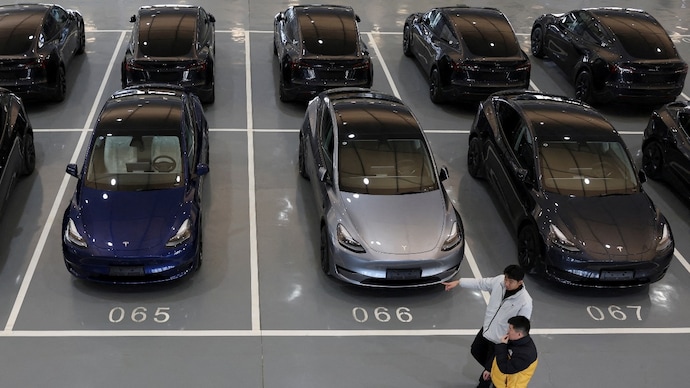 People walk past Tesla electric vehicles (EV) at the carmaker's delivery centre in Beijing, China (REUTERS/Florence Lo)