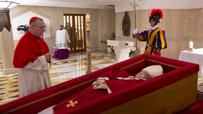Vatican Secretary of State Cardinal Pietro Parolin, left, prays in front of the body of Pope Francis laid out in state inside his private chapel at the Vatican, Monday, April 21, 2025. (Vatican Media via AP, HO) Pope