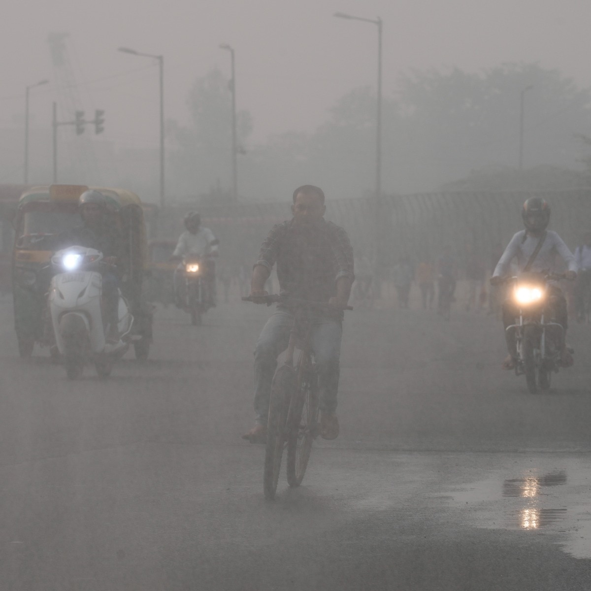 Vehicles ply on a road amid low visibility due to a thick layer of smog, in New Delhi