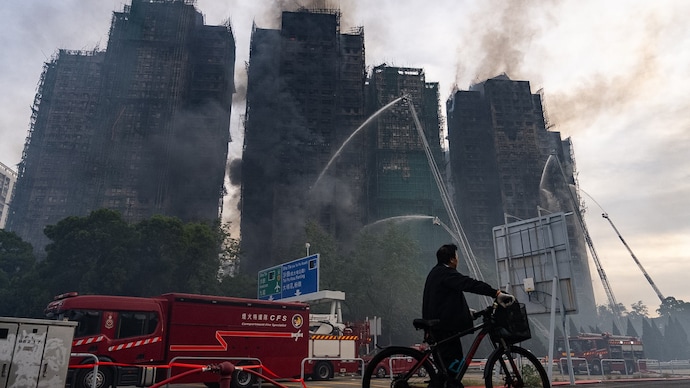 A resident looks on as firefighters work to extinguish a fire that broke out at Wang Fuk Court in Hong Kong. (AP Photo) Hong Kong fire