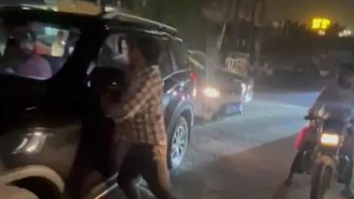 One of the men charges towards another car, and begins hitting a man sitting inside. One of the men charges towards another car, and begins hitting a man sitting inside.