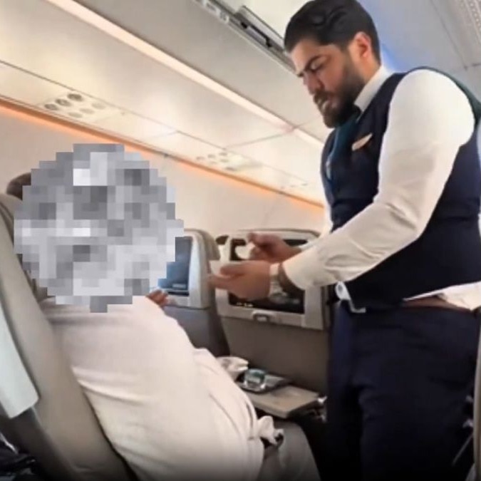 Saudia Airlines attendant feeds elderly passenger