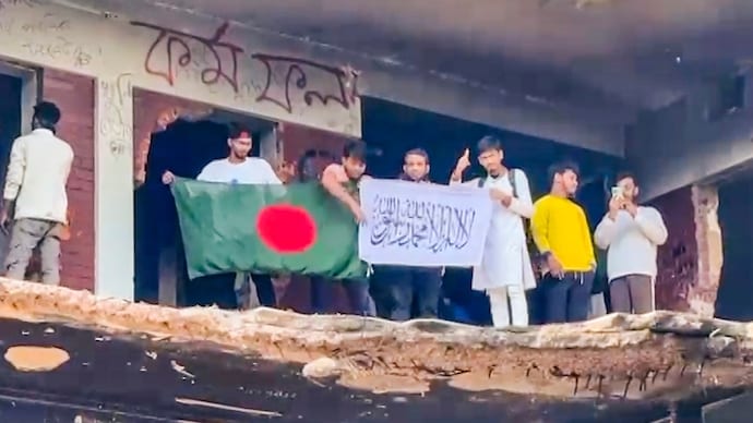 Protestors at the damaged residence of Bangladesh's founding father Sheikh Mujibur Rahman. They are holding flags of Bangladesh and the Taliban-ruled Afghanistan. (PTI Image) Protestors at the damaged premises of Bangladesh's founding father Sheikh Mujibur Rahman's home, holding flags of Bangladesh and the Taliban-ruled Afghanistan. (PTI Image)