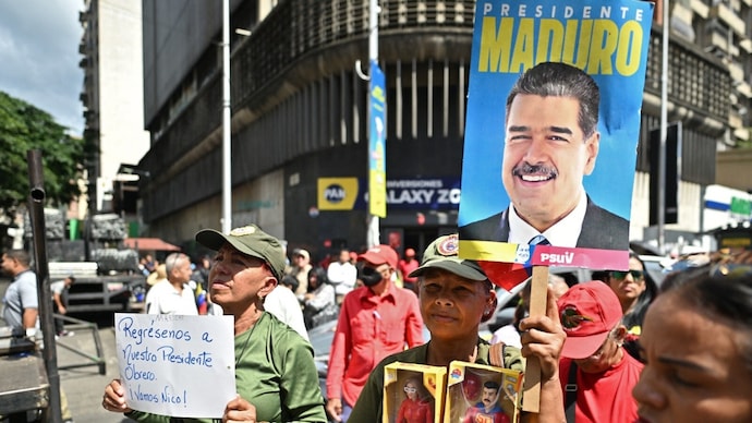 A supporter of ousted Venezuela's President Nicolas Maduro holds a poster of him, as another one holds a sign reading "Give us back our worker President. (AFP photo) A supporter of ousted Venezuela's President Nicolas Maduro holds a poster of him, as another one holds a sign reading "Give us back our worker President. (AFP photo)