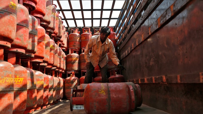 A worker unloads LPG cooking cylinders from a supply truck outside a distribution centre. (Image: Reuters) lpg shortage in india png conncection ujjwala yojana indane sms remain patient strait of hormuz iran us war middle wast global energy crisis