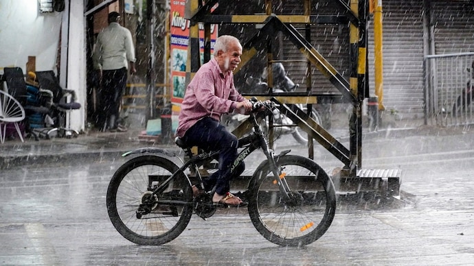 Pune: A commuter passes by on a cycle as rain lashes in various parts of Pune. (Photo: PTI) Pune rain