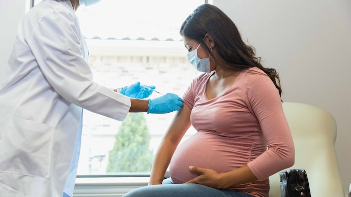 Maternal mortality refers to deaths of women during pregnancy, childbirth, or within a year after delivery due to pregnancy-related causes. (Photo: Getty Images) Wearing protective masks because of COVID-19, a mid adult pregnant woman watches as the female technician administers a booster shot.