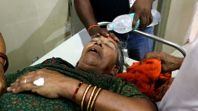 A hospital staff member pours water on the face of a patient suffering from heat stroke at a government hospital during a severe heatwave. A hospital staff member pours water on the face of a patient suffering from heat stroke at a government hospital during a severe heatwave.