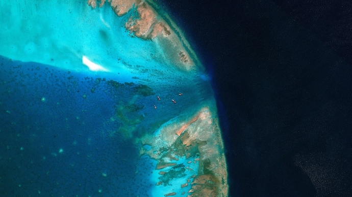 A satellite image of fishing vessels at the entrance, which is blocked by a floating barrier, to the disputed Scarborough Shoal, in the South China Sea