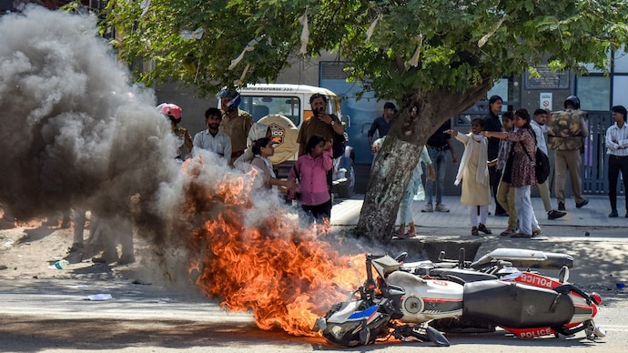 Flames billow as a police bike is set ablaze by factory workers during a protest demanding a hike in wages in Noida. (Photo: PTI) Flames billow as a police bike is set ablaze by factory workers during a protest demanding a hike in wages in Noida. (Photo: PTI)