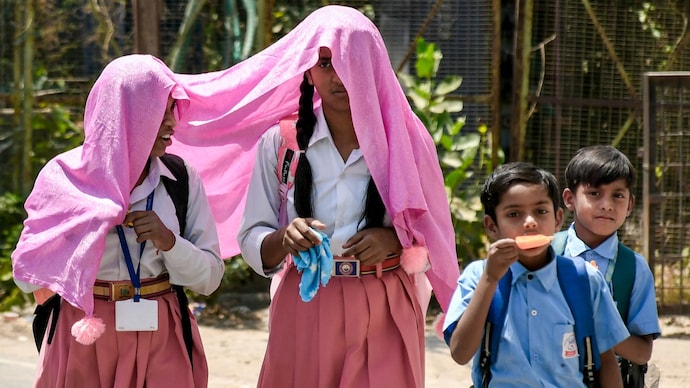 Students shield themselves from the scorching heat while returning from school. Several states have announced early summer holidays. (Image: PTI) Summer vacations news