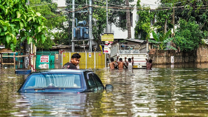 A man sits on a partially submerged car in a waterlogged area after heavy rainfall in Guwahati, Assam. (Photo: PTI) Why did Assam drown in heavy rain while rest of India faces rising heat?