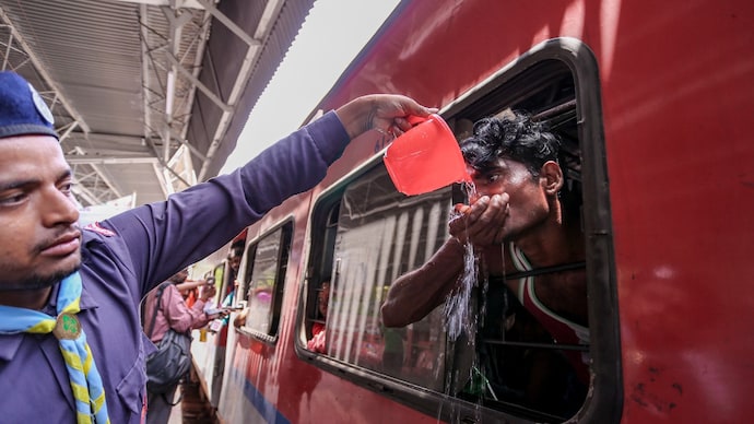 A volunteer serves drinking water to passengers amid scorching weather conditions in Prayagraj. (Image: PTI) A volunteer serves drinking water to passengers boarding a train amid hot weather conditions at the railway junction, in Uttar Pradesh's Prayagraj. (Image: PTI)