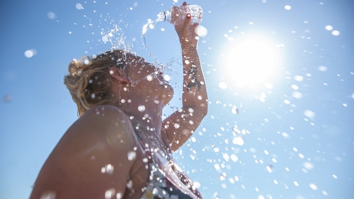 A young woman cools down with cold water during the summer heat. A young woman cools down with cold water during the summer heat.