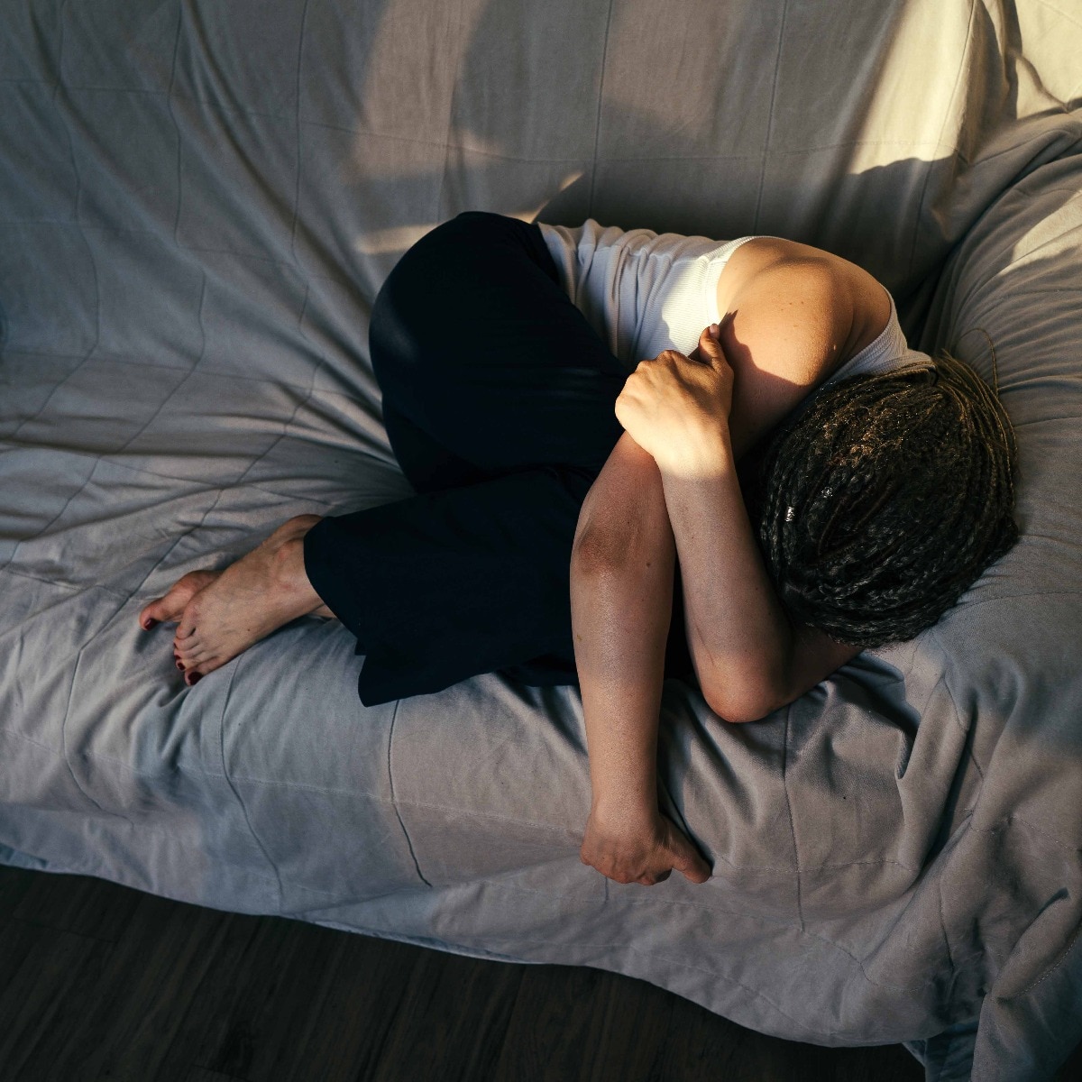 Portrait of a dreadlocks braid topknot bun woman lying and sleeping on the sofa. Concept of depression, loneliness, problems of adolescence