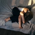 Portrait of a dreadlocks braid topknot bun woman lying and sleeping on the sofa. Concept of depression, loneliness, problems of adolescence Portrait of a dreadlocks braid topknot bun woman lying and sleeping on the sofa. Concept of depression, loneliness, problems of adolescence