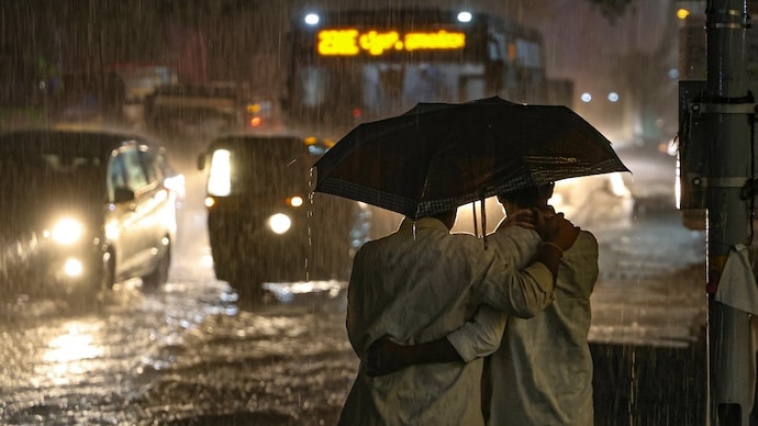 People share an umbrella as rain lashes Mysuru Road, in Bengaluru. (Photo: PTI) Rain alert India