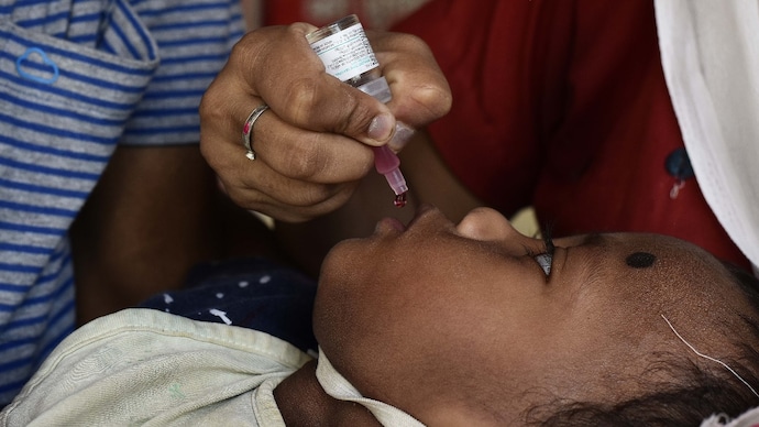 A health worker administers a dose of polio vaccine to a child during a national Pulse Polio Immunization (PPI) program at a village