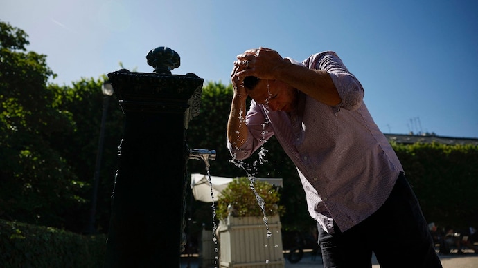 A man refresh himself by pouring water from a fountain on his hair at the Jardin du Palais Royal, central Paris