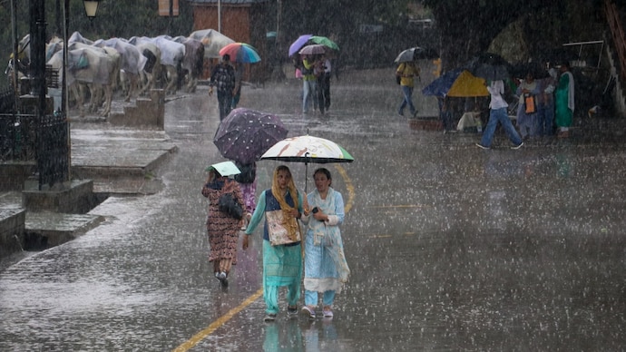 Commuters walk on a road amid rain. (Photo: PTI) Heavy rain alert: These cities to see severe weather today as monsoon hits