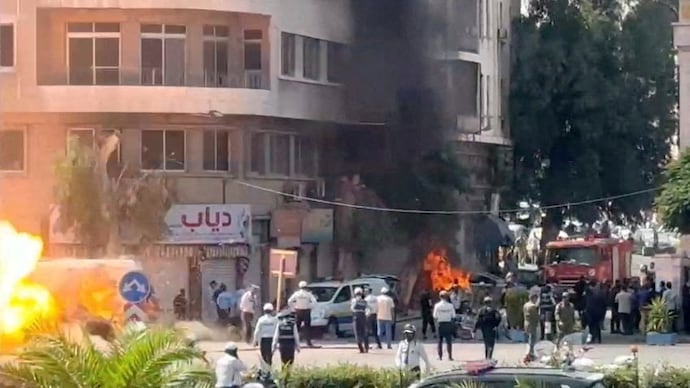 Emergency personnel work as smoke and fire rise at the site where explosive devices blew up near a hotel where French President Emmanuel Macron was meant to be staying, in Damascus, Syria. (Reuters)