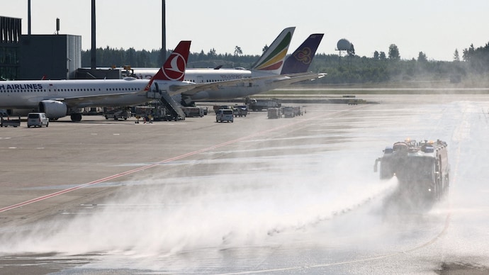 A vehicle from Oslo Airport's fire rescue services sprays water onto the runway at the airport in Oslo