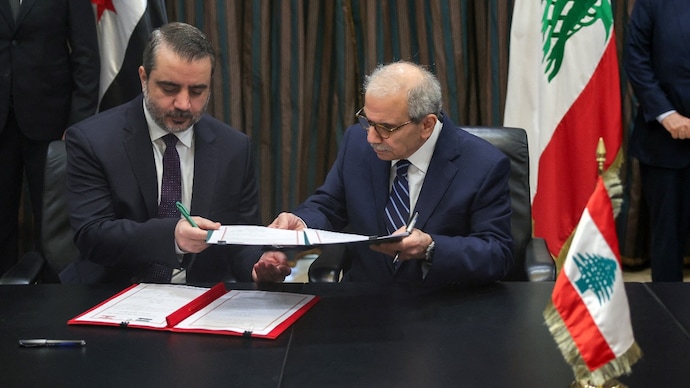 Lebanon's Prime Minister Nawaf Salam and Syria's Foreign Minister Asaad Hassan Al-Shaibani hold a document on the formation of a joint Syrian-Lebanese committee as they meet in Beirut