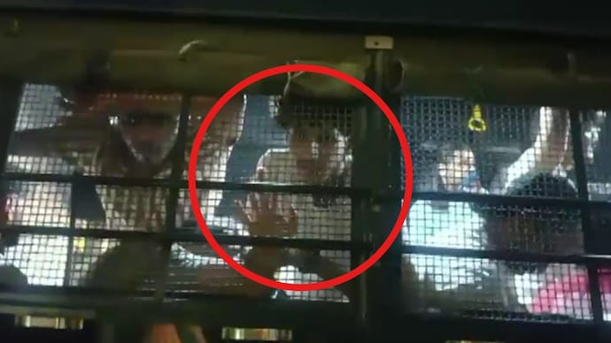 Man comforts his mother from inside the prisoner vehicle.