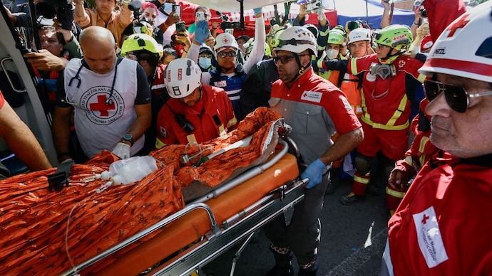 Rescue workers transport survivor Hernan Alberto Gil, who was trapped for over a week at a collapsed mall following June 24 earthquakes