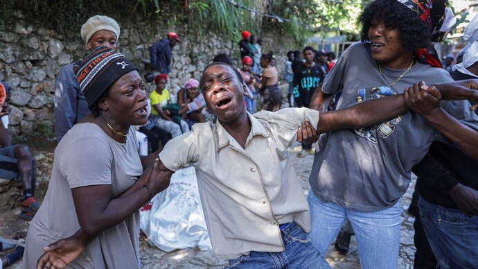 A man mourns next to the covered body of a person killed during an overnight raid by an armed gang, on the outskirts of Port-au-Prince, in Kenscoff, Haiti, August 24 ( Photo- Reuters)