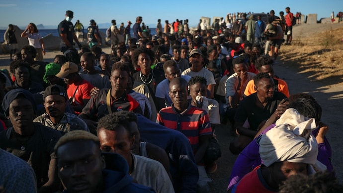 Migrants wait in line to receive food and beverage from the Red Cross following mass crossings on foot and by sea from Morocco into Ceuta.