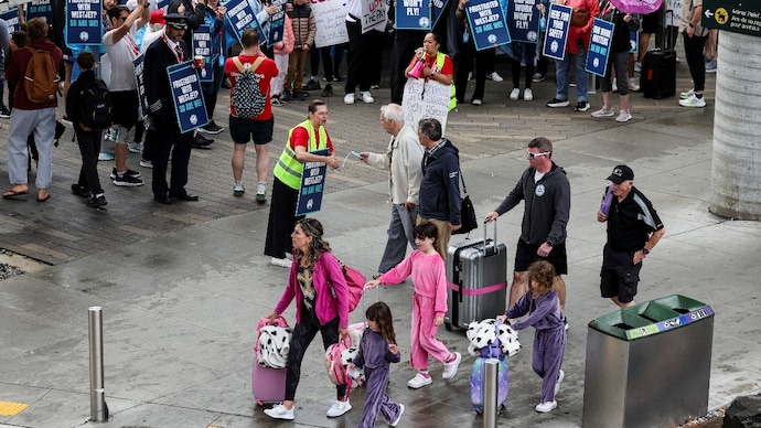 Passengers walk by as protesters take part in a picket line, after flight attendants at Canada's WestJet go on strike. ( Photo- Reuters)