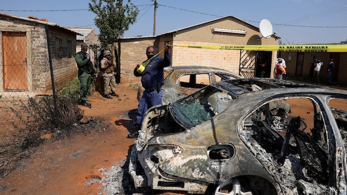 Emergency personnel cordon off an area next to burnt vehicles at the site of a deadly shooting at a tavern in Wedela township, southwest of Johannesburg. Emergency personnel cordon off an area next to burnt vehicles at the site of a deadly shooting at a tavern in Wedela township, southwest of Johannesburg.