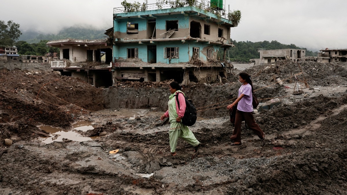 People walk past damaged houses following deadly flash floods and a mudslide, in Nuwakot district, Nepal on September 21, 2026. (Photo: Reuters)