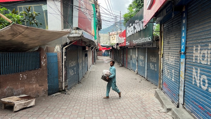 A man walks with his belongings along a closed market in Muzaffarabad, POK. (File Photo: Reuters) A man walks with his belongings along a closed market in Muzaffarabad, POK. (File Photo: Reuters)