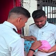 Traffic police personnel hold the newborn after a woman gave birth at a traffic police chowki outside Surat Railway Station. Traffic police personnel hold the newborn after a woman gave birth at a traffic police chowki outside Surat Railway Station.