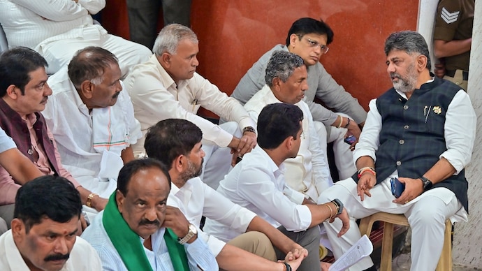 Shivakumar combined his attack on the alleged misuse of voter deletion applications with a broader push on doorstep governance, welfare measures and land-related services. (Credits: PTI) Karnataka Chief Minister DK Shivakumar with his cabinet colleagues stage a 'dharna' on the premises of the Chief Electoral Officer's office. (Image: PTI)