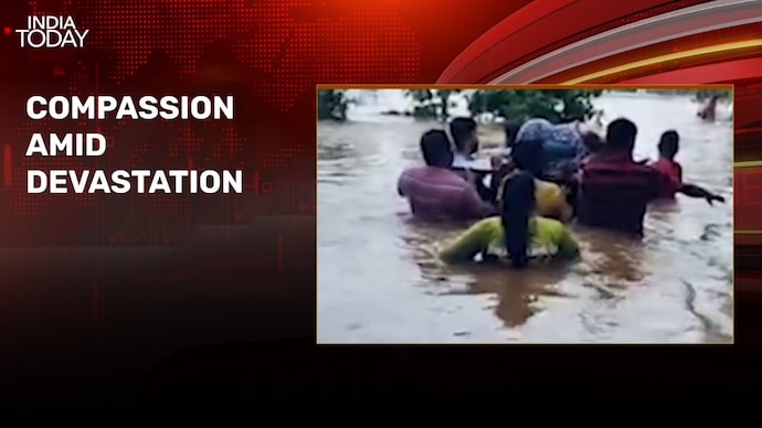 Locals carry pregnant woman on wooden door through chest-deep water amid flood