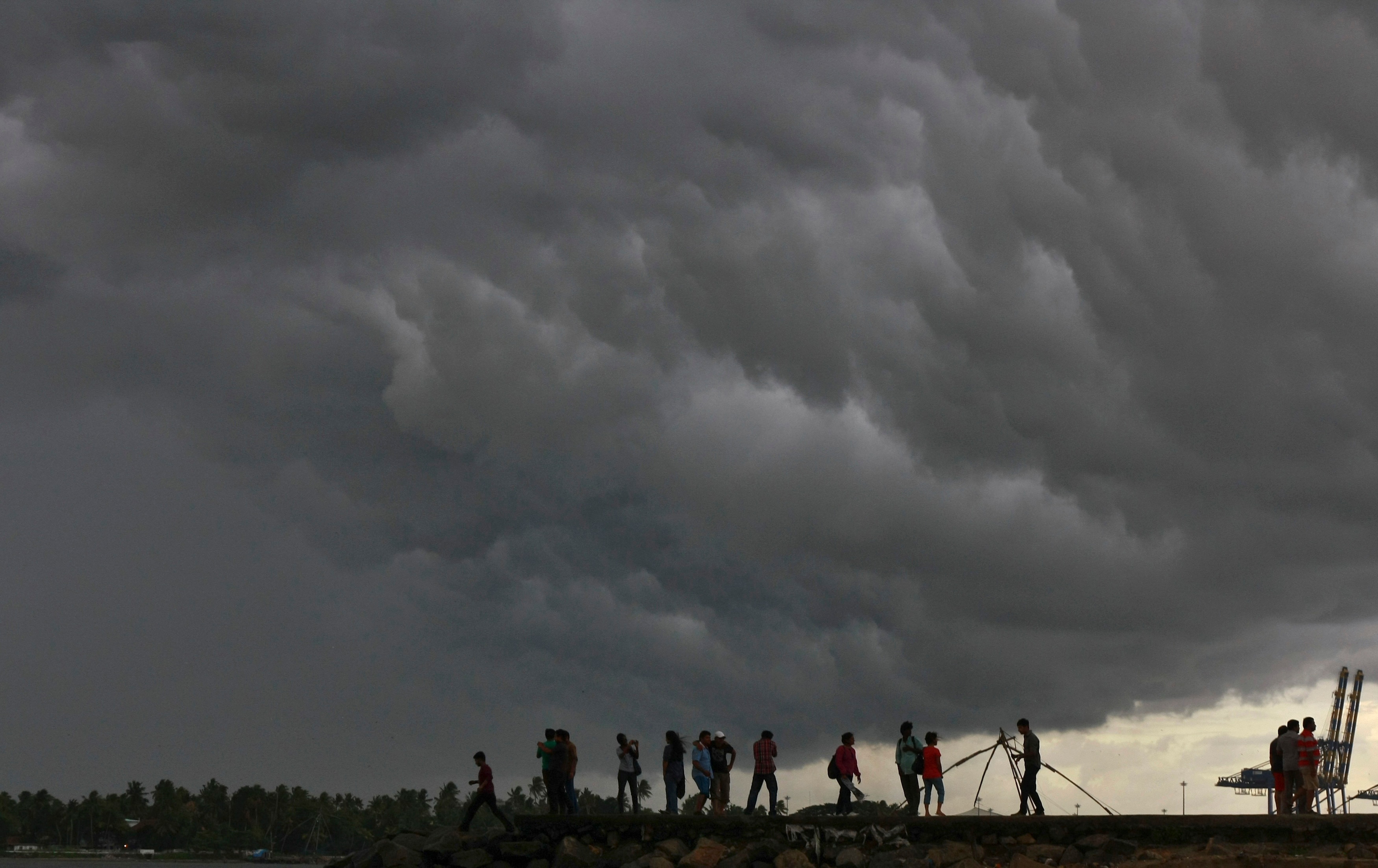 People stand on a seaside promenade as pre-monsoon clouds gather. (Photo: Reuters)