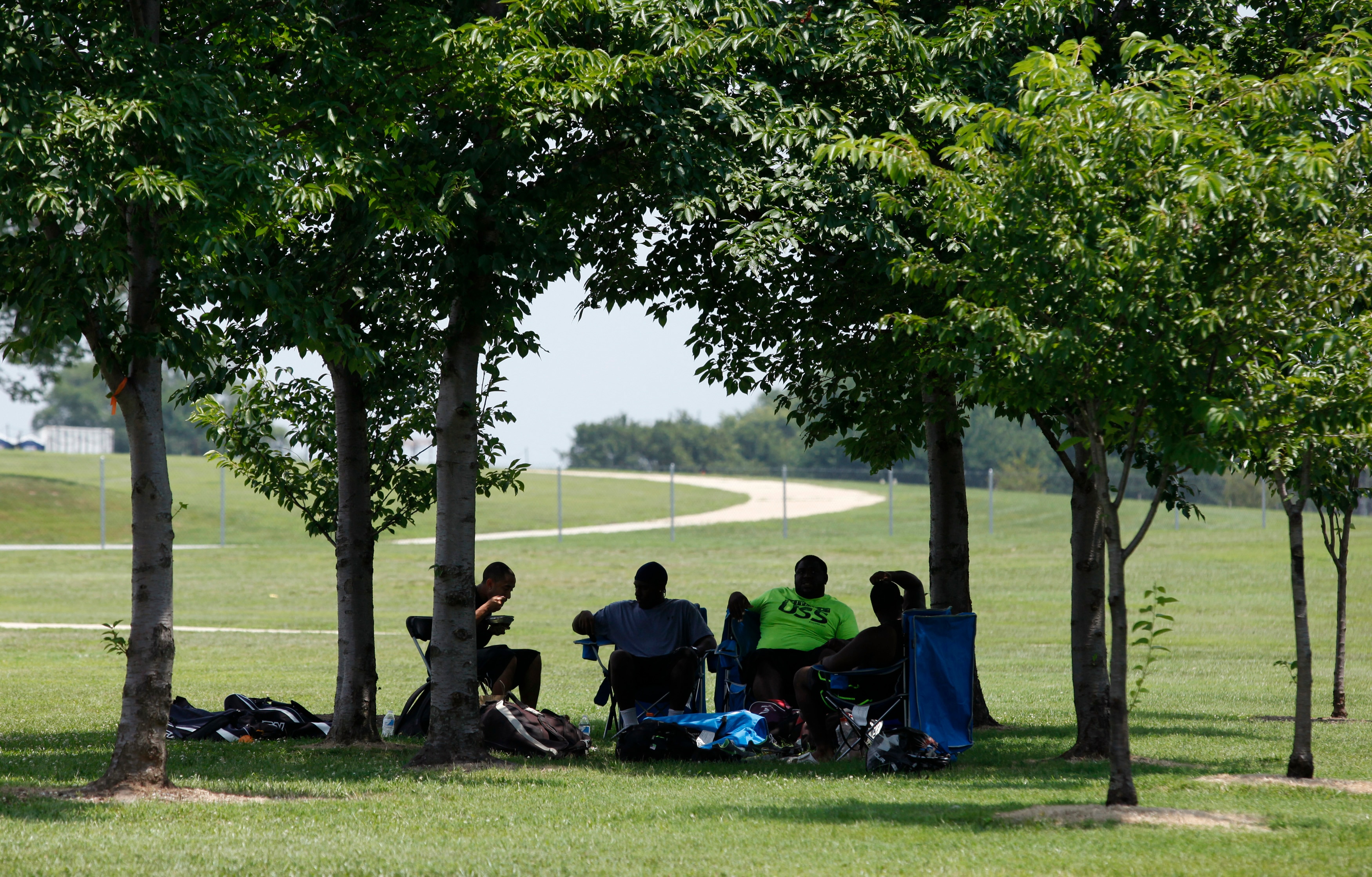 People relax under trees during a heatwave. (Photo: Reuters)