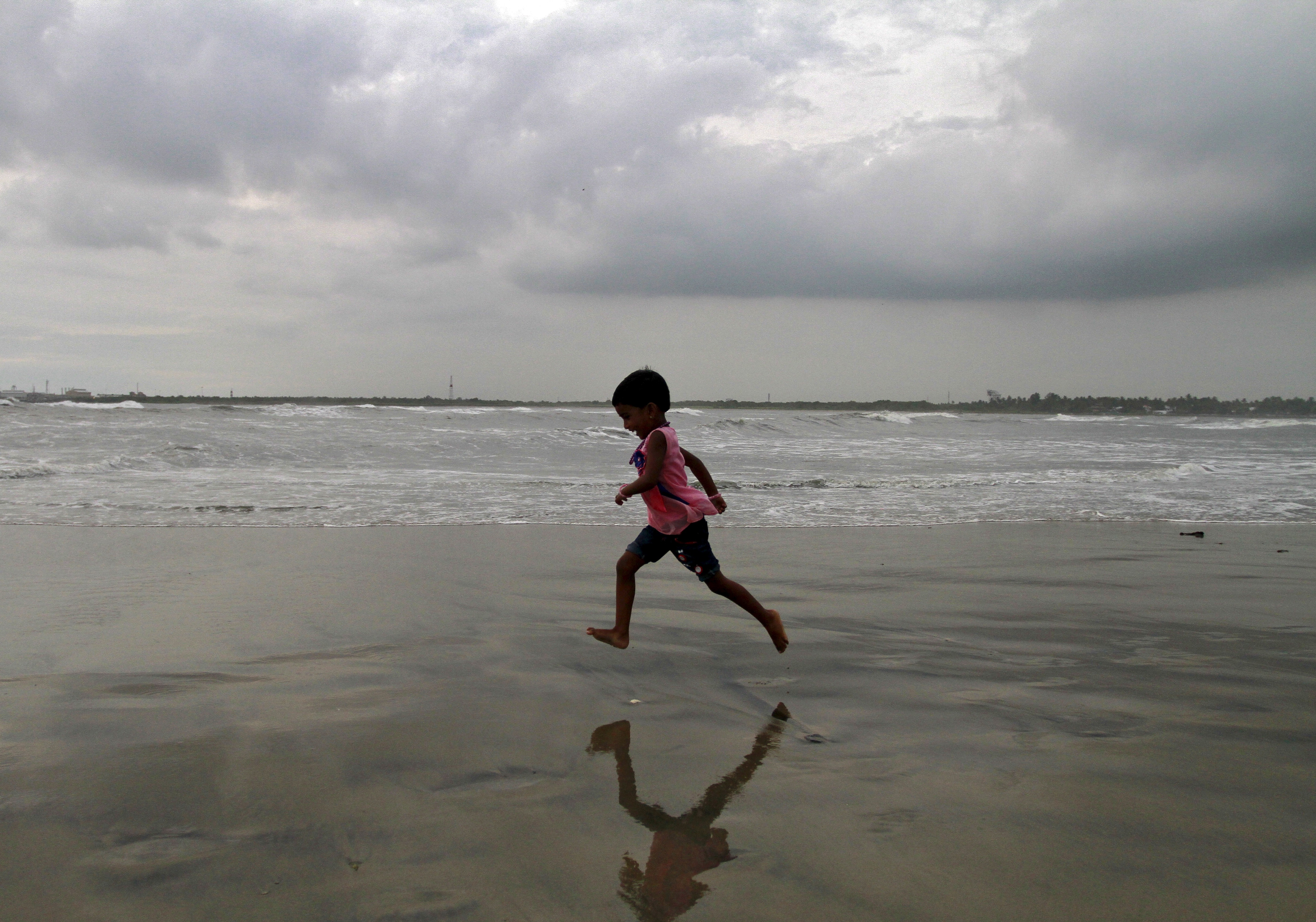 A girl runs against the backdrop of monsoon clouds at a beach in Kerala. (Photo: Reuters)