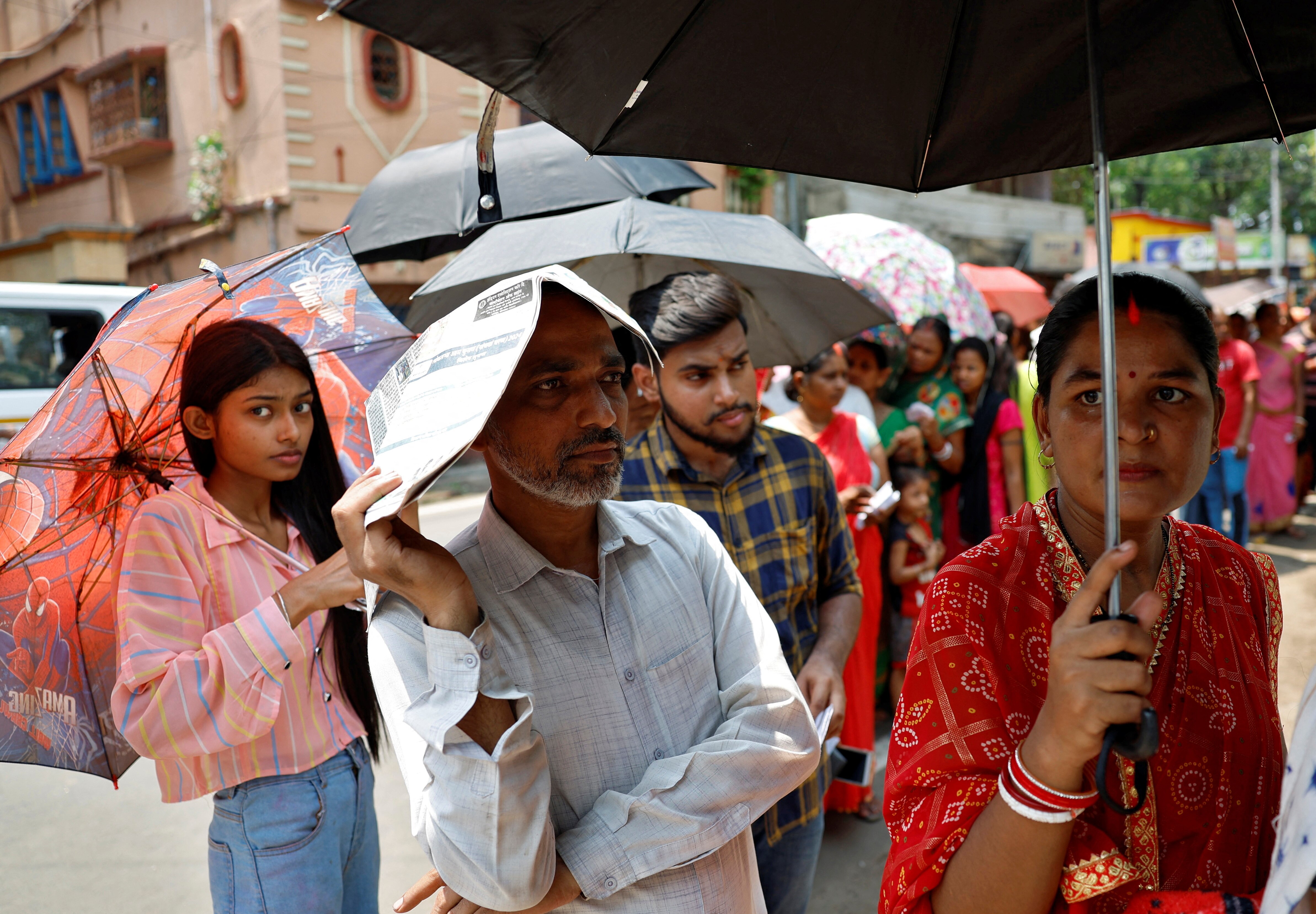 People protect themselves from the heat as they wait to vote outside a polling station in West Bengal. (Photo: Reuters)