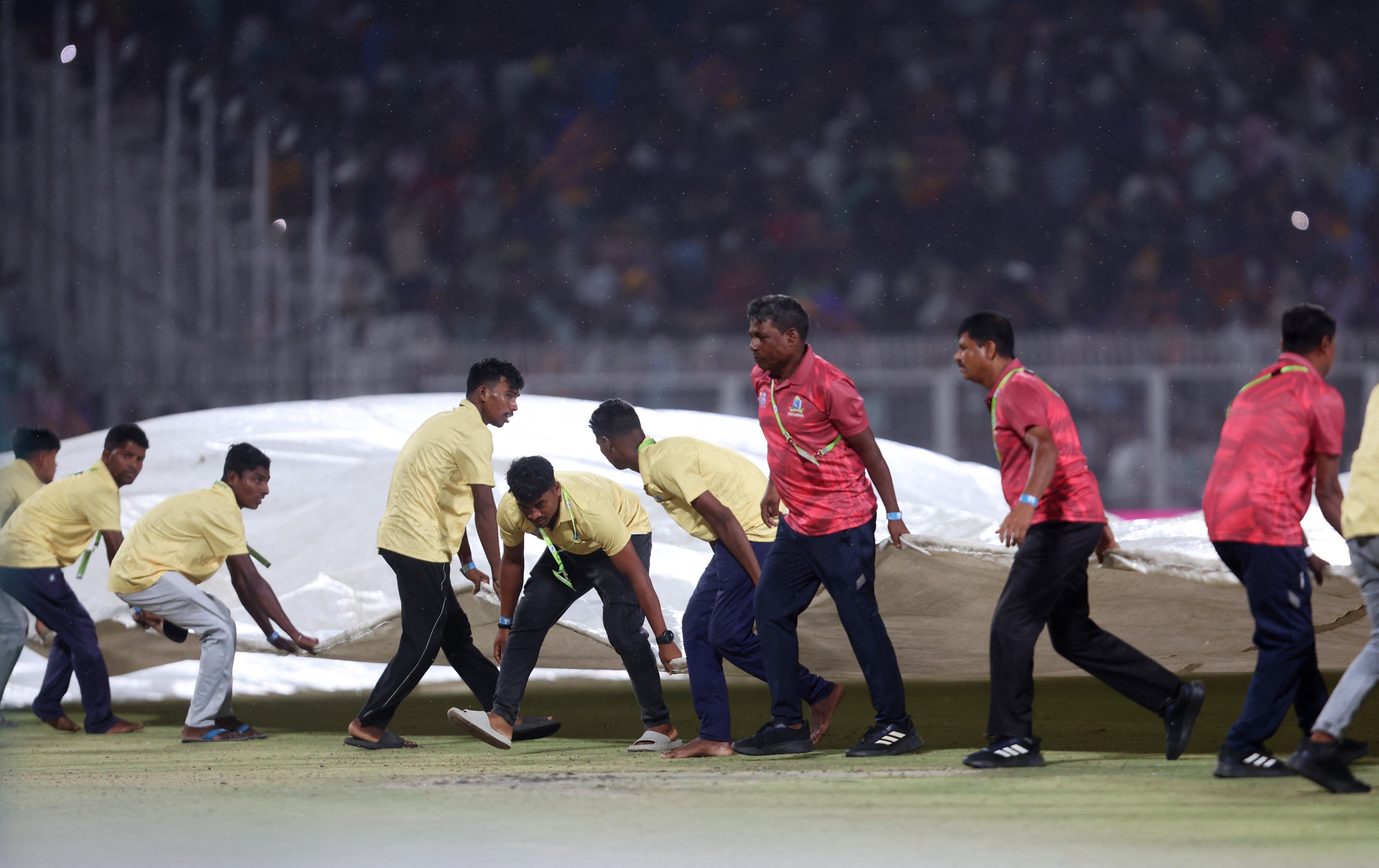 Groundstaff at the Eden Gardens stadium in Kolkata work together to pull in the covers during the KKR vs PBKS match in IPL 2025. (Image: Reuters)