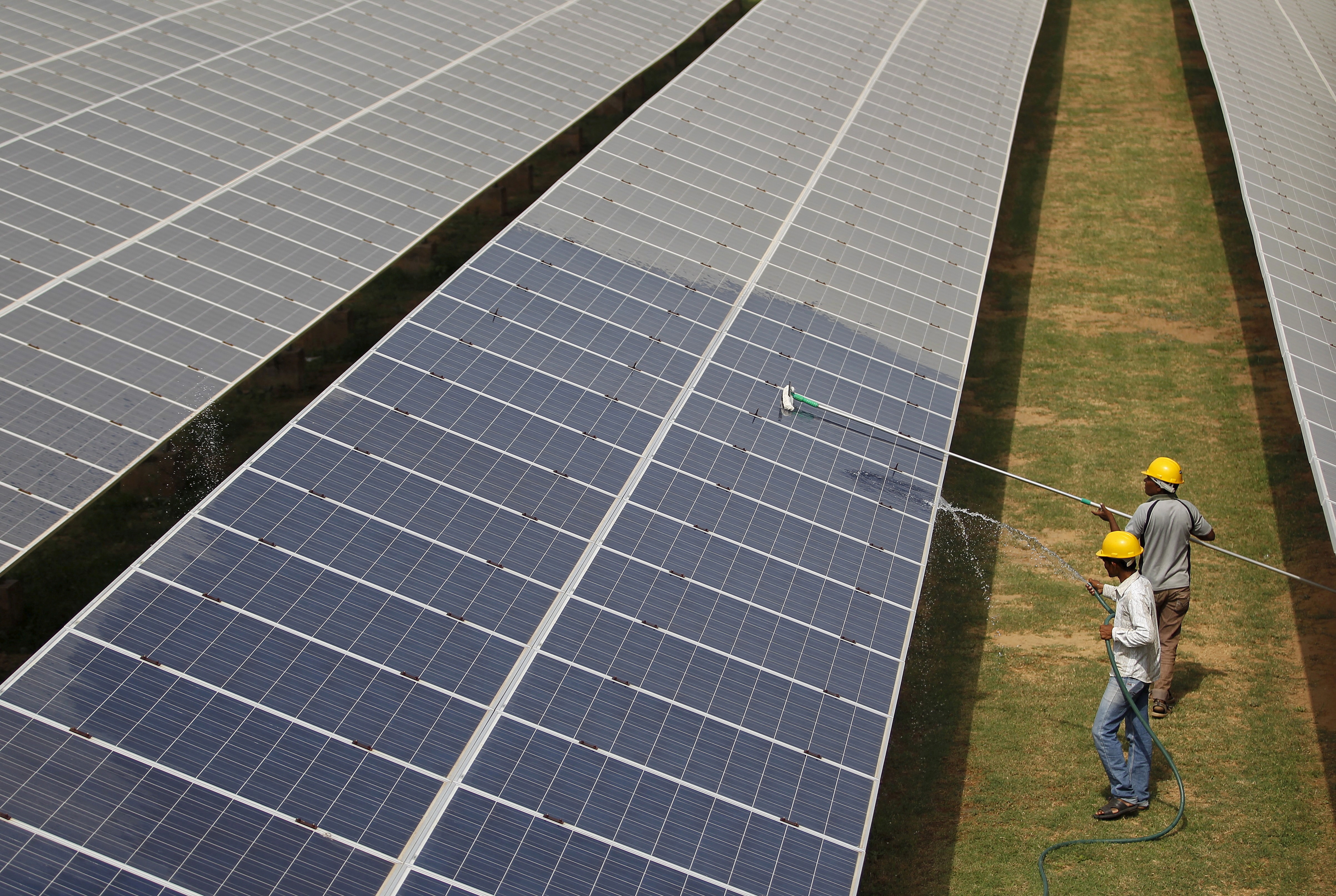 Workers clean photovoltaic panels inside a solar power plant in Gujarat. (Photo: Reuters)