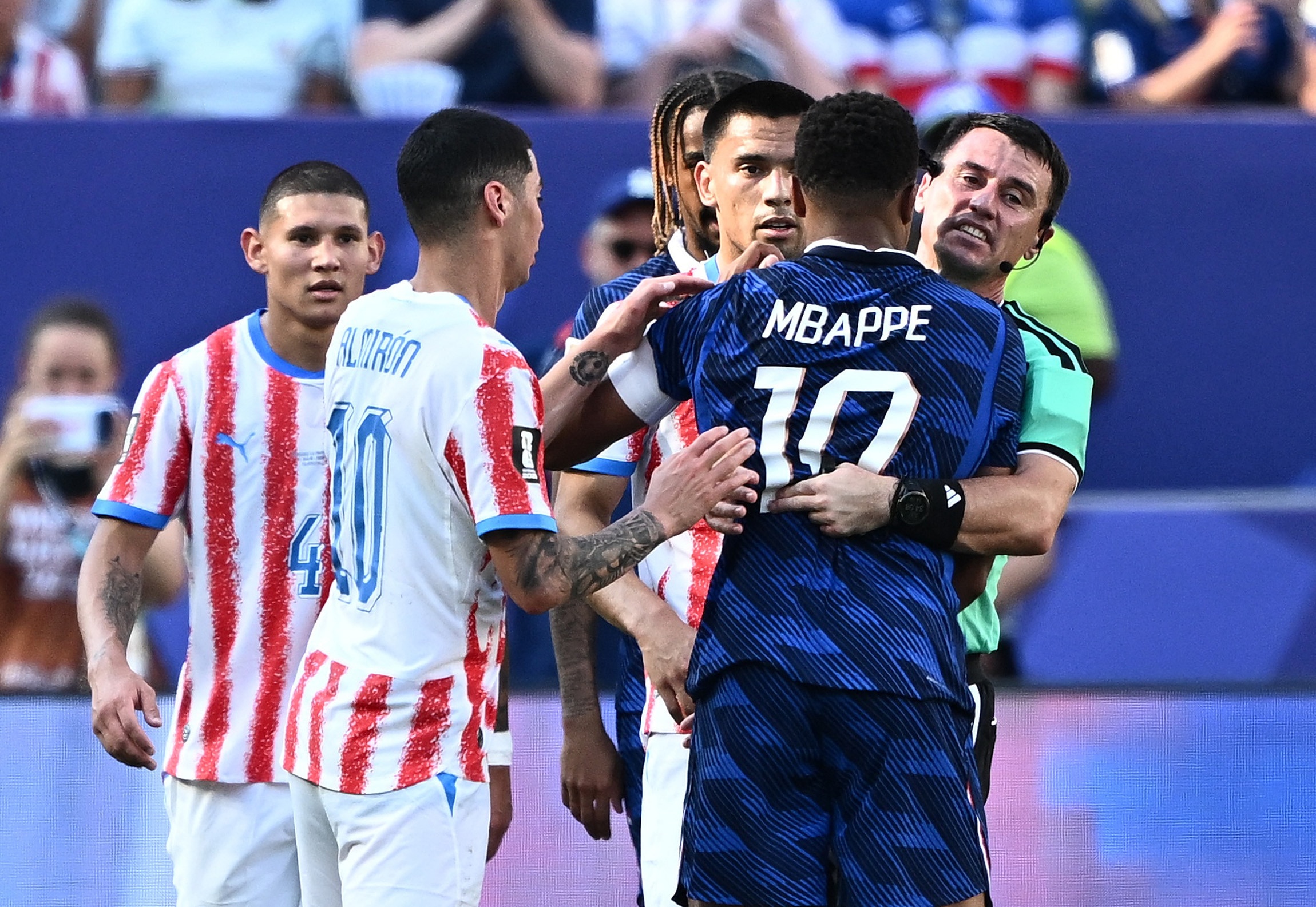 France's Kylian Mbappe is being held back by the referee during their game against Paraguay in the FIFA World Cup 2026. (Image: Reuters)