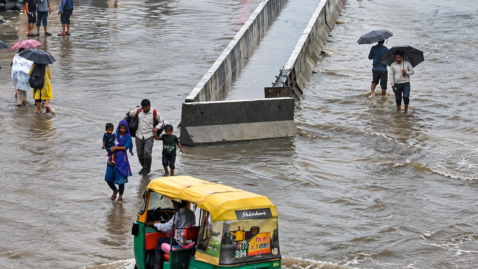 People wade through waterlogged streets after heavy rainfall. (File Photo)