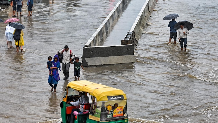 People wade through waterlogged streets after heavy rainfall. (File Photo)