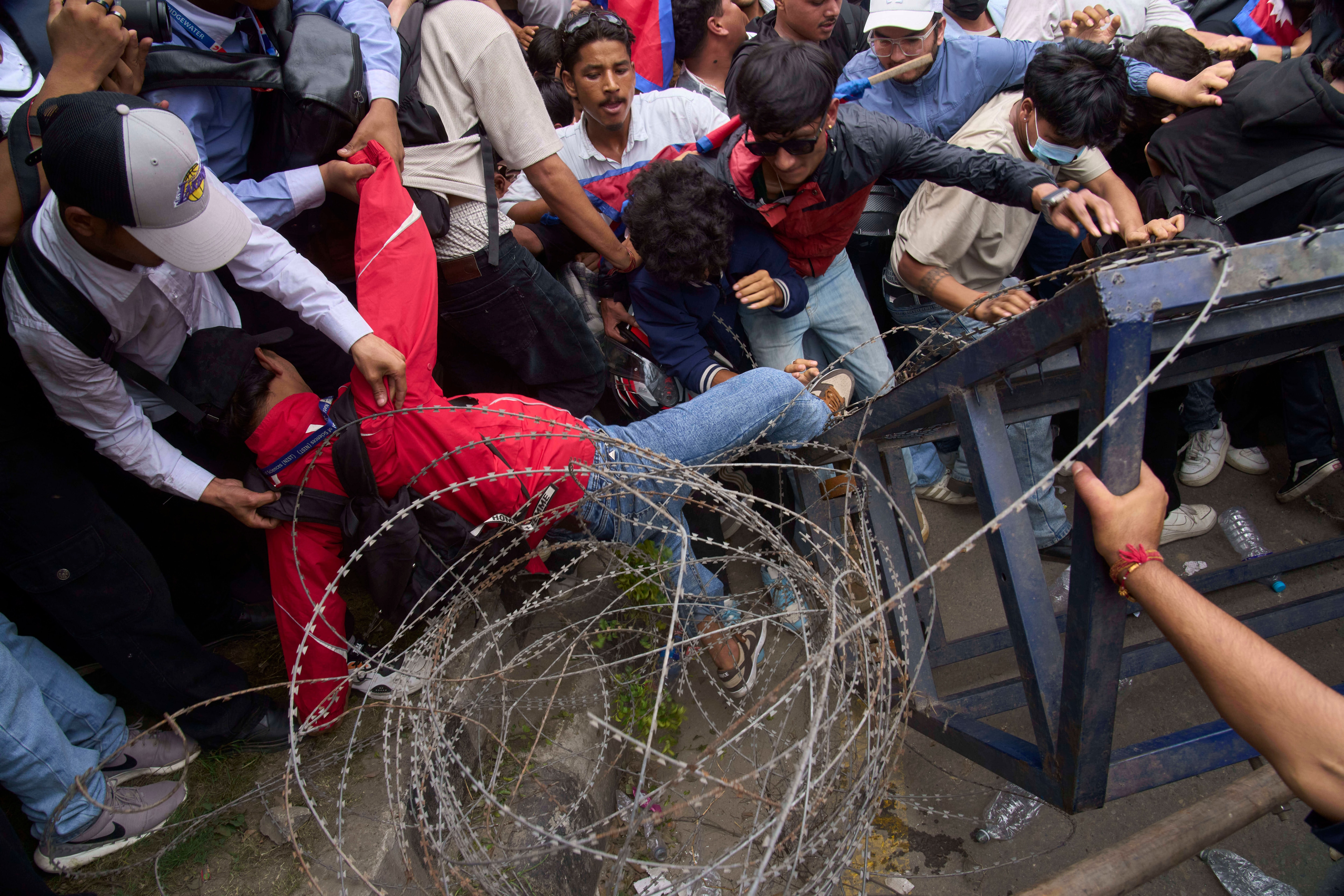 A protester falls down during clashes with riot police outside the parliament building in Kathmandu, Nepal, Monday, Sept. 8, 2025. 